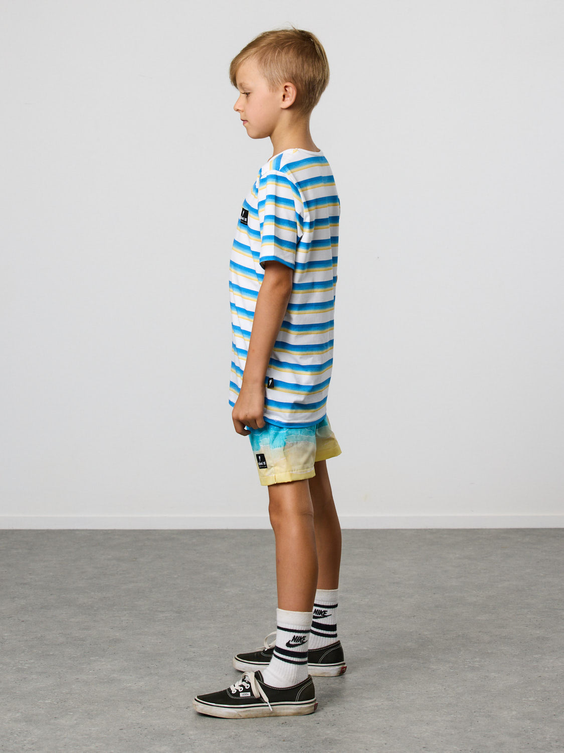 Radicool Kids beach stripe tee: Cotton / spandex tee in white with beach waves printed in horizontal stripes. Radicool Dude badge on chest. We love a stripe, even more when it’s the colours of the beach! Fit is true to size.